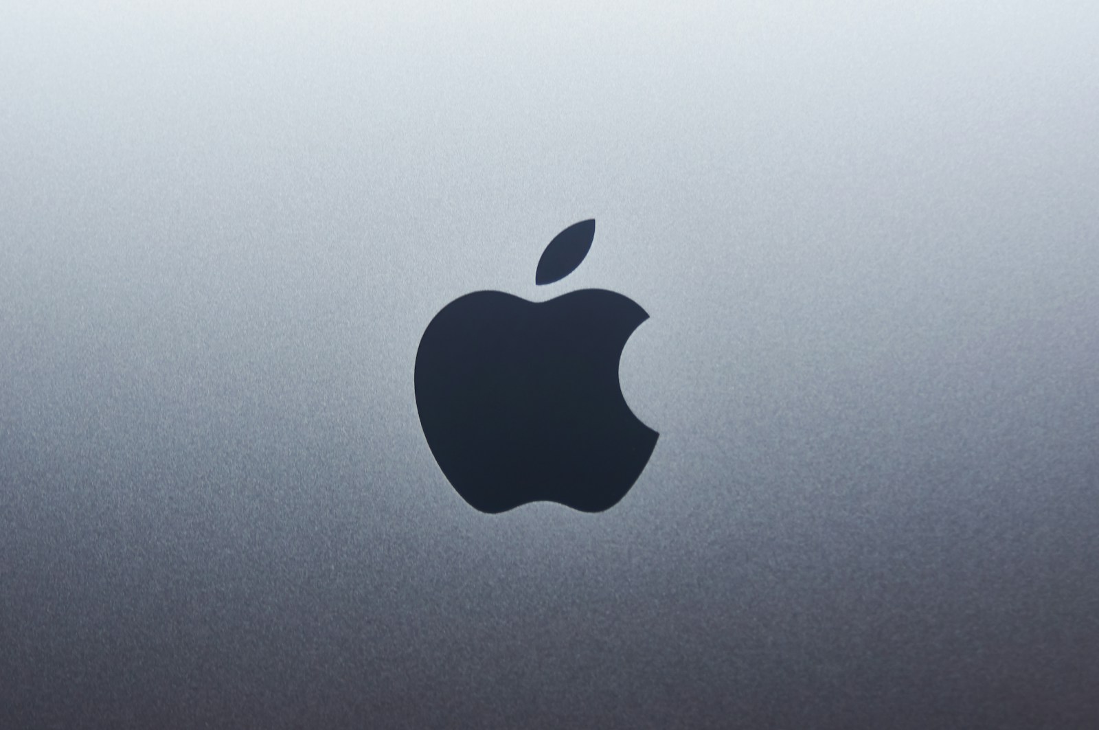 Appleのガバナンス記事に使う、金属面に置かれた黒いAppleロゴ