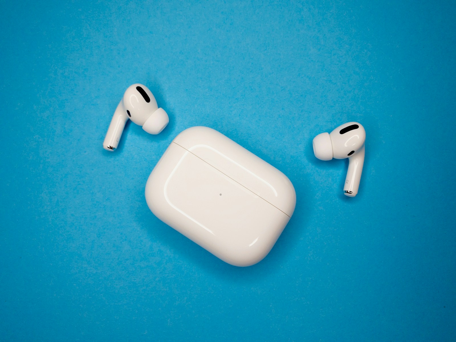 White AirPods Pro earbuds and charging case on a blue background