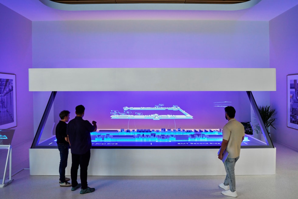 Visitors examining the holographic production-line table inside Apple's Advanced Manufacturing Center in Houston