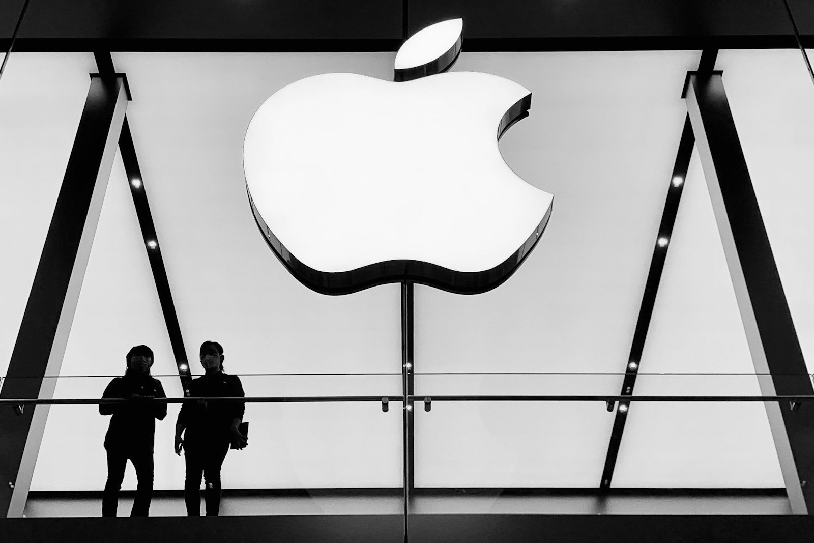 Deux personnes en silhouette sous le logo Apple lumineux d’un Apple Store à Chengdu, en Chine.