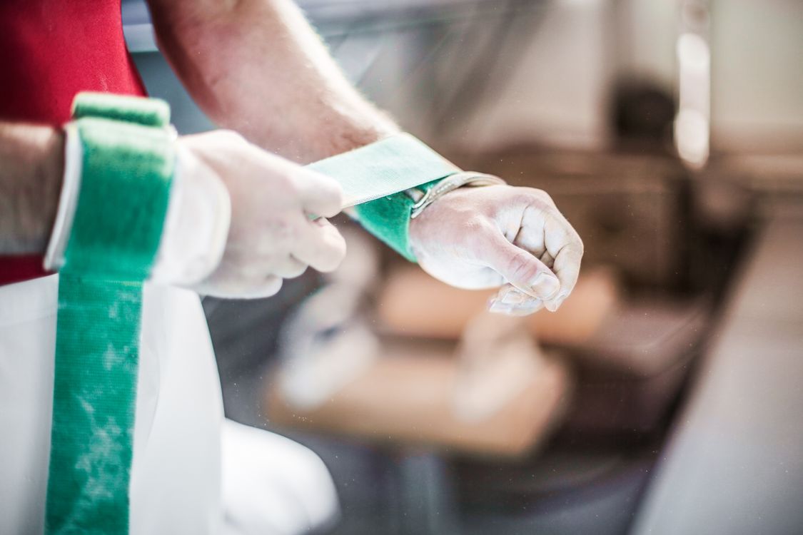 An athlete wrapping a green wrist support before a workout
