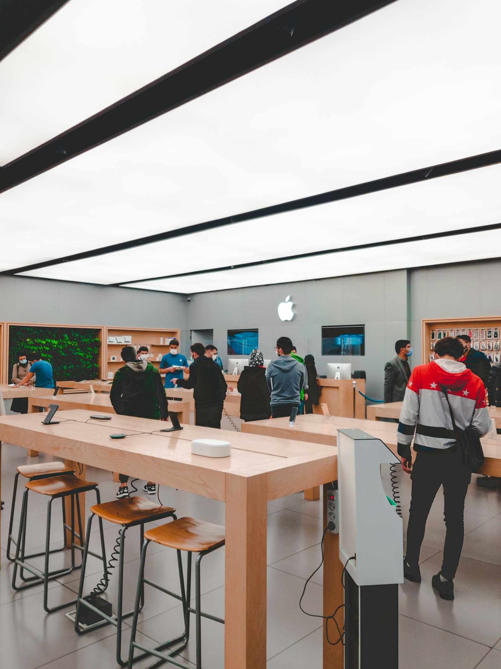 Varios clientes recorren las mesas de demostración del interior de una Apple Store; fotografía ilustrativa sobre la cadena de suministro del iPhone 18.