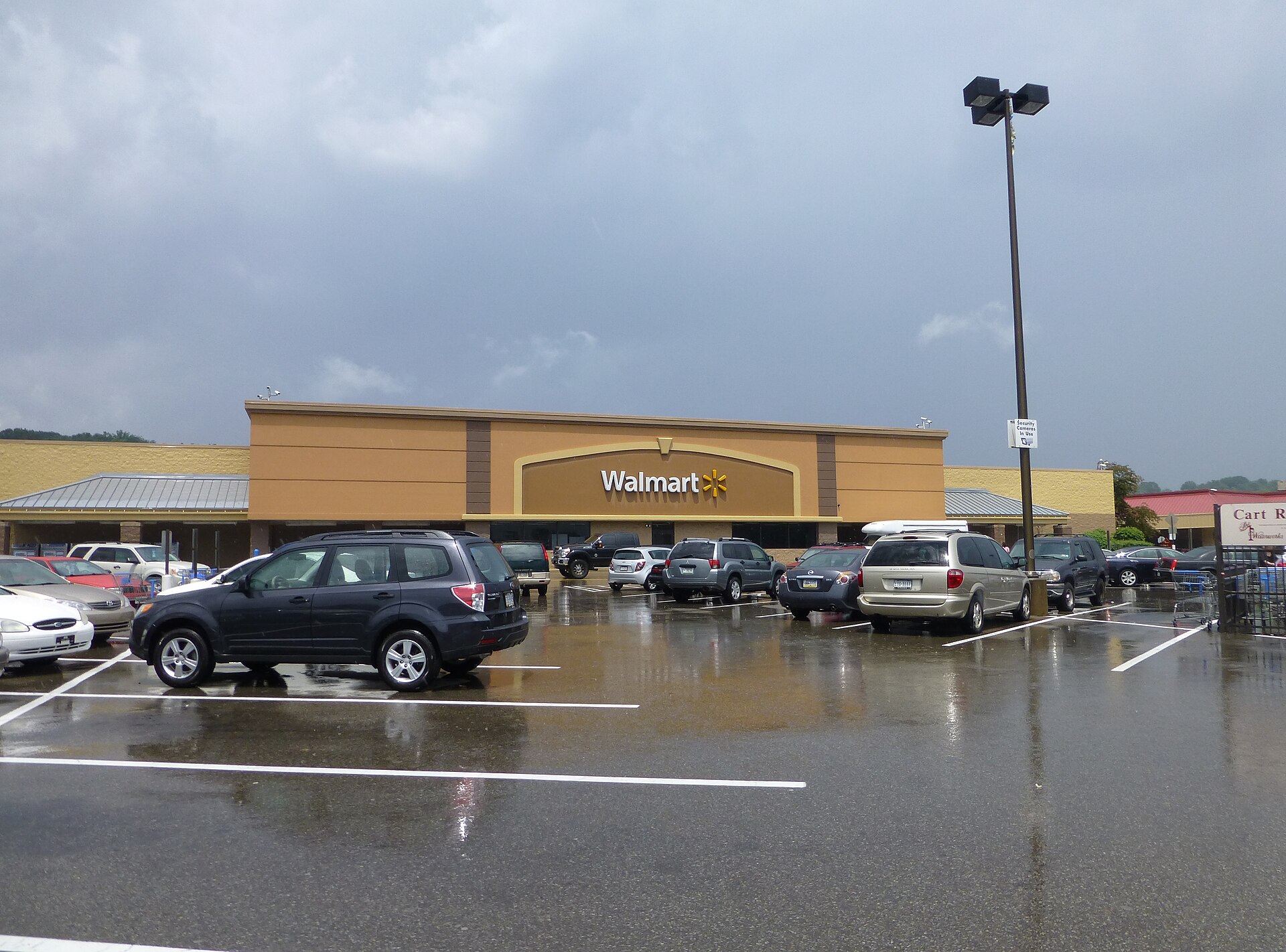 A Walmart store and its recognizable spark logo in a rainy American parking lot