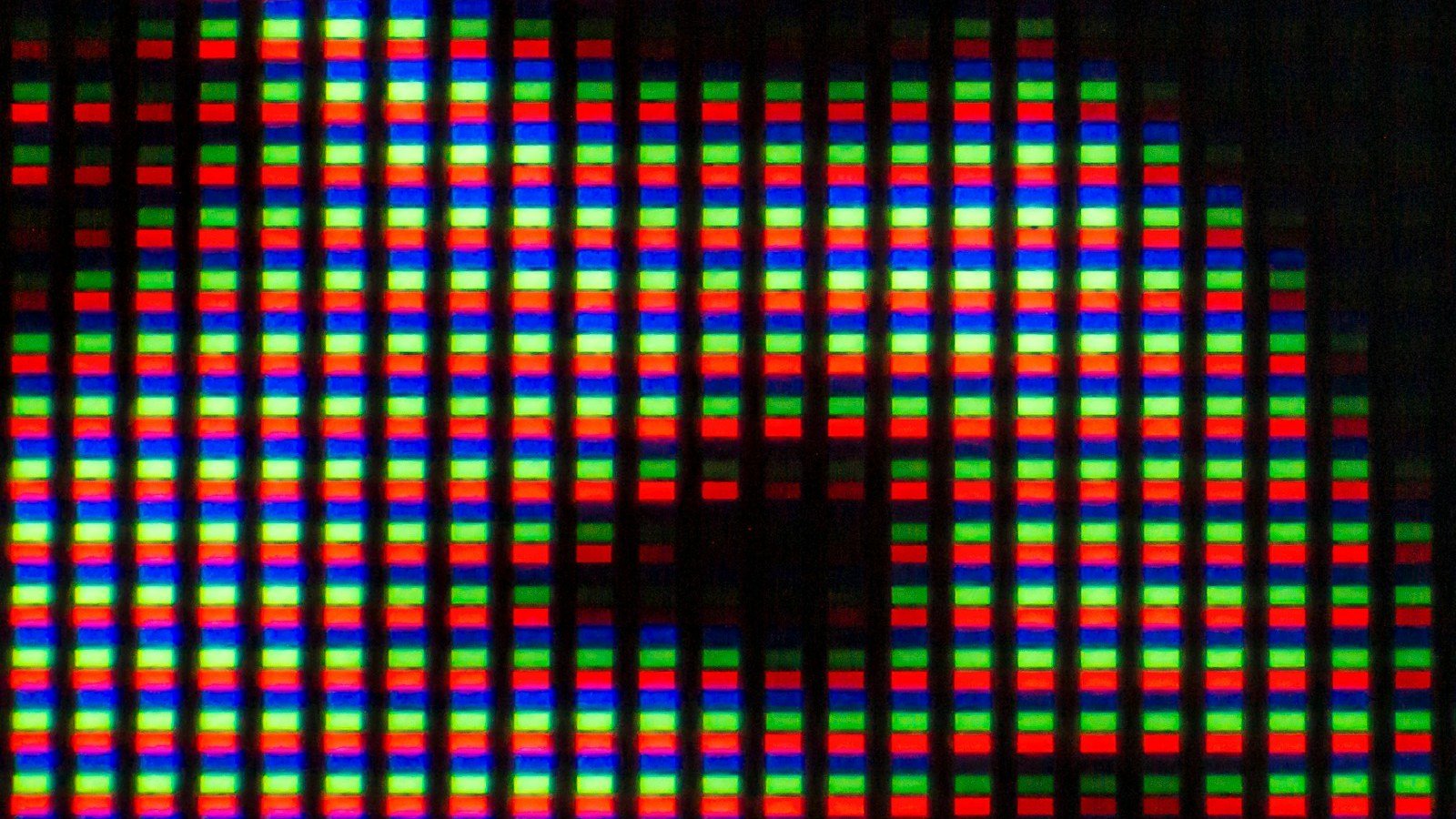 Macro photograph of a display's red, green and blue subpixels and the dark gaps between them. Illustrative image: not an Apple screen and not the iPhone Duo.