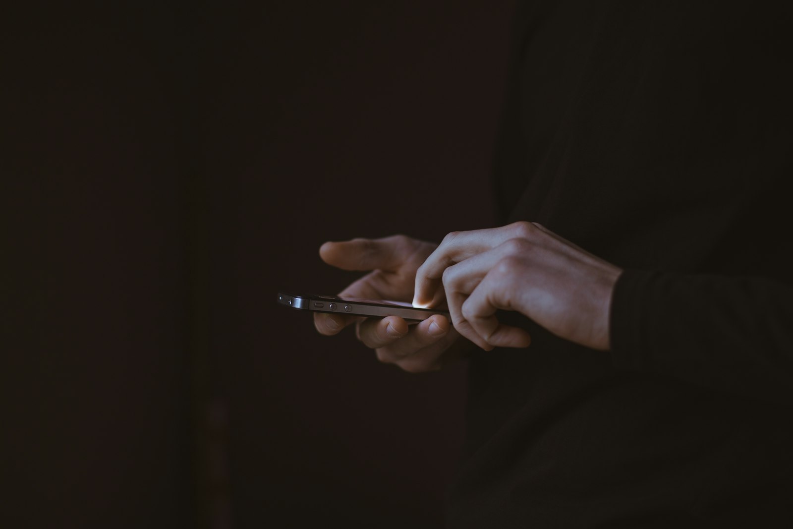 Hands holding a smartphone in low light