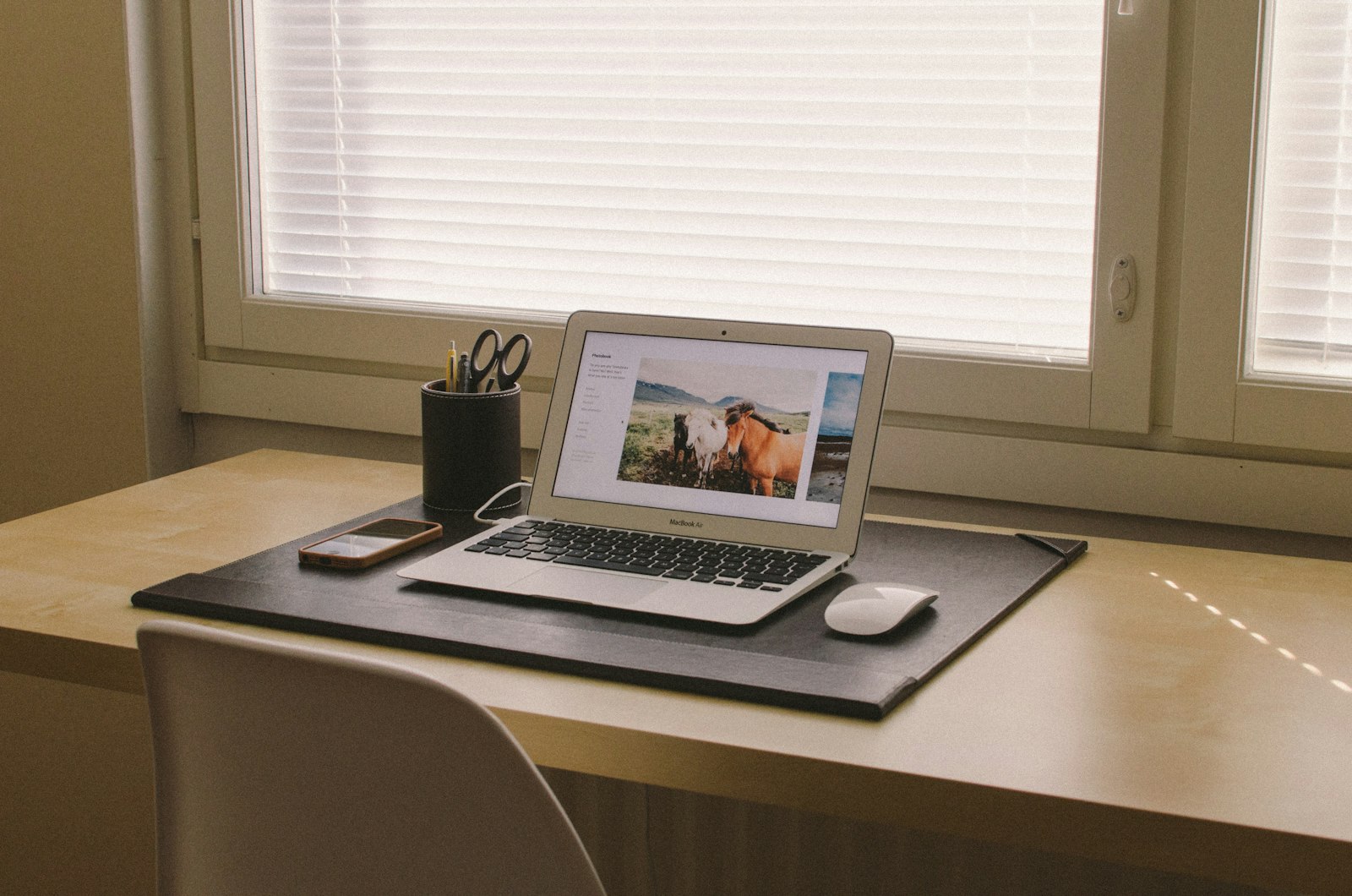 MacBook turned on sitting on beige wooden desk